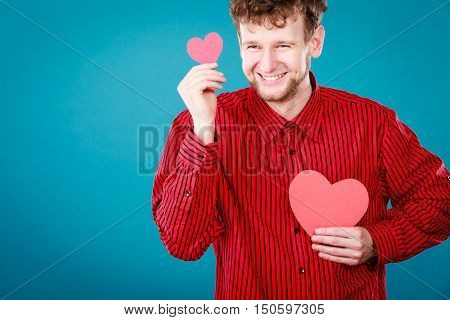 Love and help from people. Charming lovely man with two red paper hearts persuade to be good helpful hopeful. Valentines Day or charity concept.