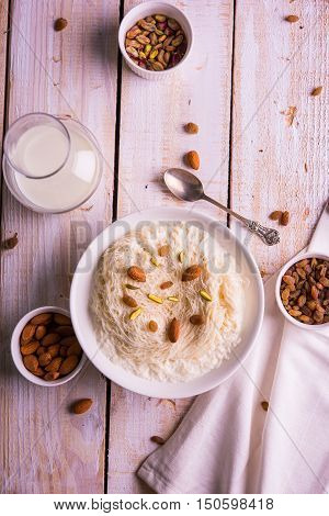 Indian sweet sutarfeni or sutar feni or firni or seviyan or laccha, shredded, flaky-rice-flour roasted in ghee, blended with melted sugar to form a cotton candy, topped with pistachio and almonds