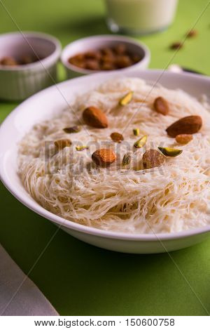 Indian sweet sutarfeni or sutar feni or firni or seviyan or laccha, shredded, flaky-rice-flour roasted in ghee, blended with melted sugar to form a cotton candy, topped with pistachio and almonds