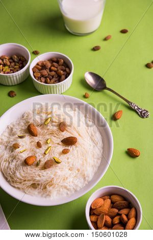 Indian sweet sutarfeni or sutar feni or firni or seviyan or laccha, shredded, flaky-rice-flour roasted in ghee, blended with melted sugar to form a cotton candy, topped with pistachio and almonds