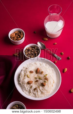 Indian sweet sutarfeni or sutar feni or firni or seviyan or laccha, shredded, flaky-rice-flour roasted in ghee, blended with melted sugar to form a cotton candy, topped with pistachio and almonds