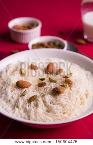 Indian sweet sutarfeni or sutar feni or firni or seviyan or laccha, shredded, flaky-rice-flour roasted in ghee, blended with melted sugar to form a cotton candy, topped with pistachio and almonds