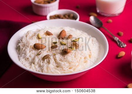Indian sweet sutarfeni or sutar feni or firni or seviyan or laccha, shredded, flaky-rice-flour roasted in ghee, blended with melted sugar to form a cotton candy, topped with pistachio and almonds
