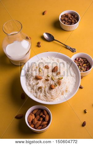 Indian sweet sutarfeni or sutar feni or firni or seviyan or laccha, shredded, flaky-rice-flour roasted in ghee, blended with melted sugar to form a cotton candy, topped with pistachio and almonds