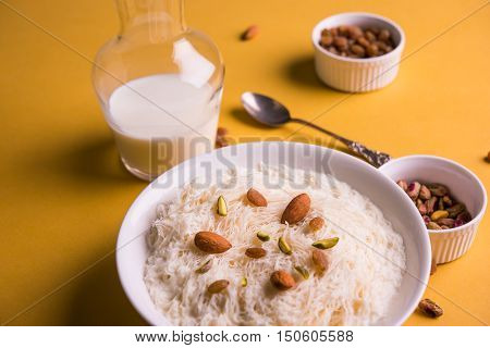 Indian sweet sutarfeni or sutar feni or firni or seviyan or laccha, shredded, flaky-rice-flour roasted in ghee, blended with melted sugar to form a cotton candy, topped with pistachio and almonds