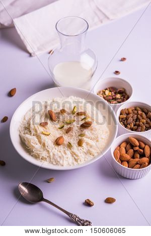 Indian sweet sutarfeni or sutar feni or firni or seviyan or laccha, shredded, flaky-rice-flour roasted in ghee, blended with melted sugar to form a cotton candy, topped with pistachio and almonds