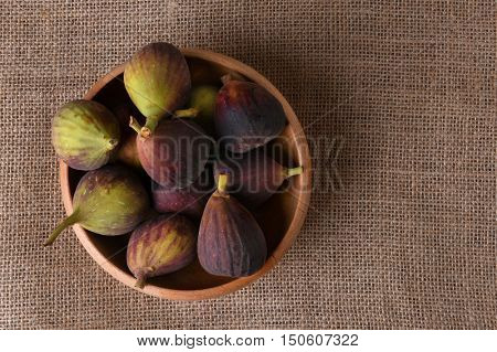 A wood bowl full of fresh picked figs. horizontal format with copy space. 