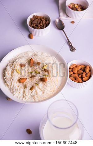 Indian sweet sutarfeni or sutar feni or firni or seviyan or laccha, shredded, flaky-rice-flour roasted in ghee, blended with melted sugar to form a cotton candy, topped with pistachio and almonds