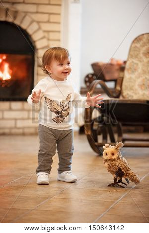 The happy child little girl standing at home against fireplace