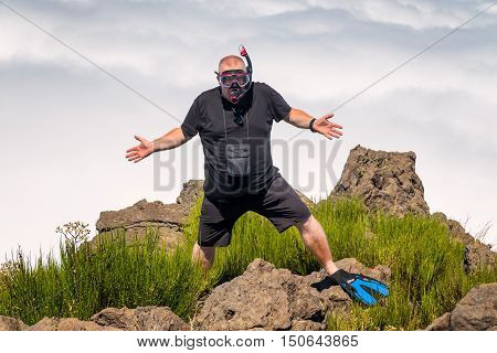 Obese diver confused he is at top of the mountain instead shore of the sea.