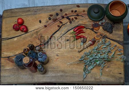 still life of bottles peppers in pots and mint on wooden surface