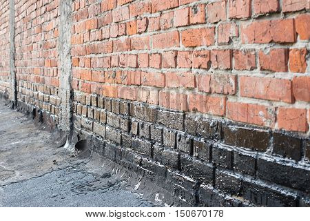 Covered brick wall bitumen primer for improving adhesion during surfacing contiguity with rolled waterproofing during the installation of flat roof.