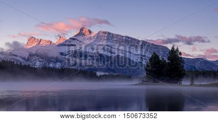 Rundle Mountain reflecting in Two Jack Lake in Banff National Park at sunrise.