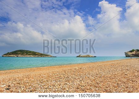 Gargano coast: Baia di Campi beach,Vieste-(Apulia) ITALY-The pebbly beach is a picturesque bay sheltered the south by the Campi rock,framed by olive trees and pinewoods.On background Campi islet.