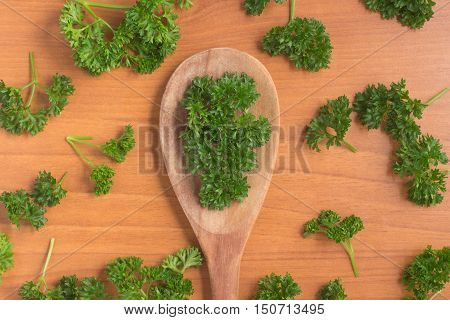 Parsley into a spoon over a wooden table