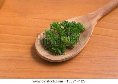 Parsley into a spoon over a wooden table