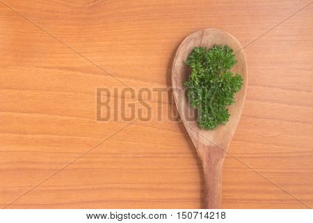 Parsley into a spoon over a wooden table