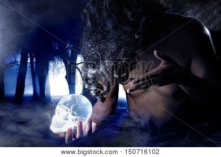 Primitive looking man in a dark smoky forest as a witch doctor or shaman