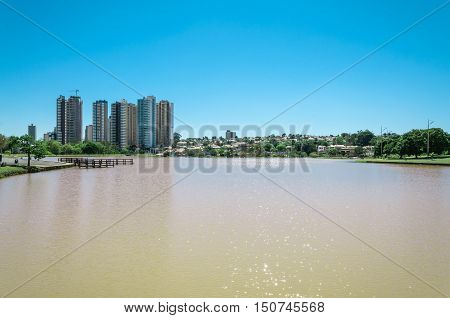 Park pond with city background and blue sky. Sunny day, landscape in a horizontal photo.