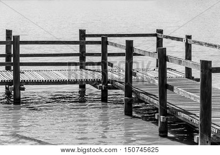 Wooden footbridge over water lake in a park. Black and white photo.