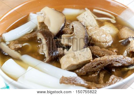 Vegetarian chinese roll noodle soup whit shiitake mushroom and tofu on wood table in Vegetarian festival