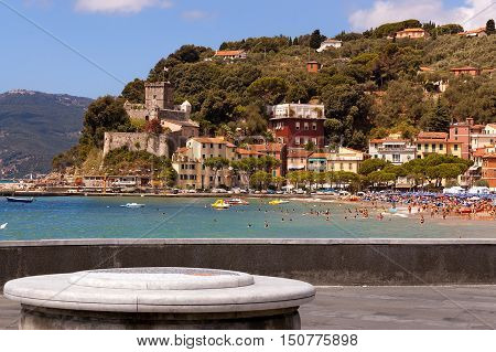 The village of San Terenzo (St. Terenzo) with the beach crowded with sunbathers. Lerici in the Gulf of La Spezia Liguria Italy
