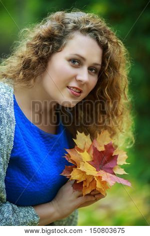 beautiful young plussize model in the autumn park with yellow leaves in her hands