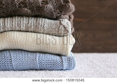 Stack of cozy knitted warm sweater on your home background . Sweaters in retro Style. The concept of warm .