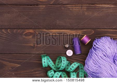 Purple thread crochet , buttons and measuring tape on wooden table. The view from the top. Sewing accessories.