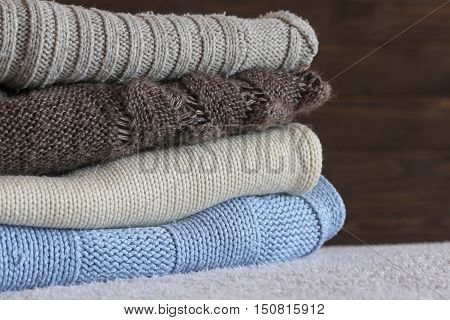 Stack of cozy knitted warm sweater on your home background . Sweaters in retro Style. The concept of warm .