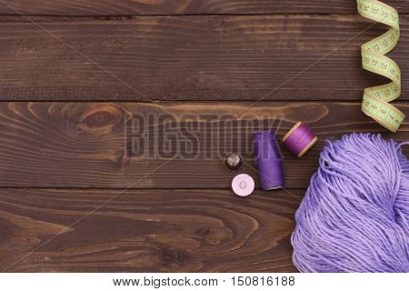 Purple thread crochet , buttons and measuring tape on wooden table. The view from the top. Sewing accessories.