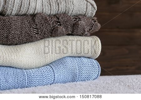Stack of cozy knitted warm sweater on your home background . Sweaters in retro Style. The concept of warm .