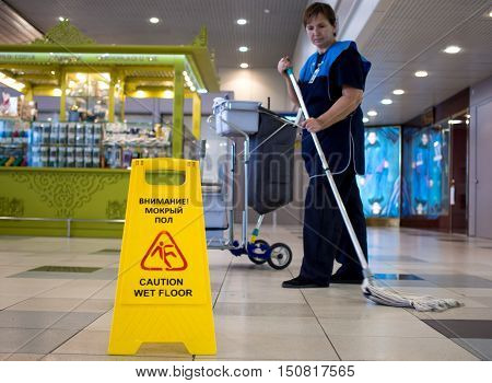 Moscow, Russia - November 07, 2015: Elderly woman - the cleaning lady cleans tile floor in the hall of Domodedovo airport.