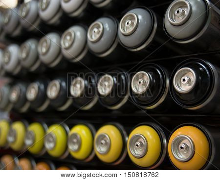 bottles with spray paint lie in rows on the counter