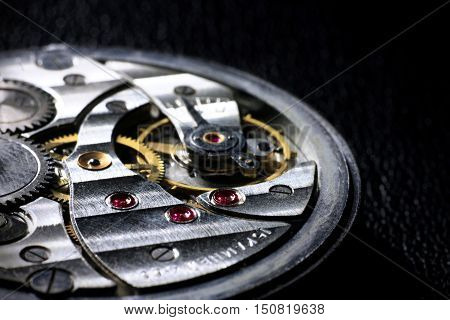Pocket watch inside close up with wheels springs and rubies on dark background