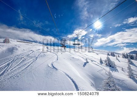 Skiers on the chair lift enjoying the view to Tyrolian Alps in Austria and beautiful snowy country panorama in famous Kitzbuehel mountain ski resort