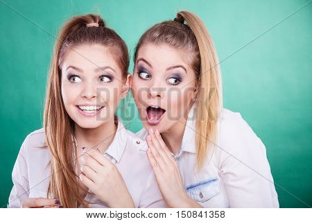 Young woman telling her friend some secrets two women talking gossiping. Excited emotional girl whispering to human ear