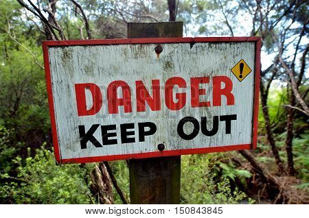 Danger keep out wooden sign panel posted in the wilderness. concept photo of travel and outdoor activity.