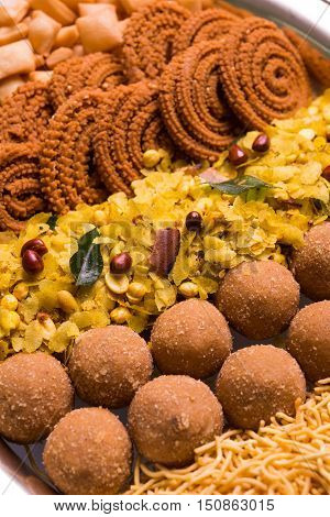 Plate full of indian festival food or diwali food or snacks like laddu, chivda, chakali or murukku, sev and shankar pale, sweet and salty snack food