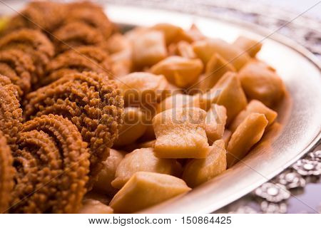 Plate full of indian festival food or diwali food or snacks like laddu, chivda, chakali or murukku, sev and shankar pale, sweet and salty snack food