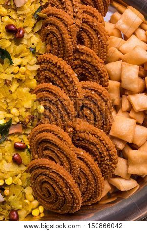 Plate full of indian festival food or diwali food or snacks like laddu, chivda, chakali or murukku, sev and shankar pale, sweet and salty snack food