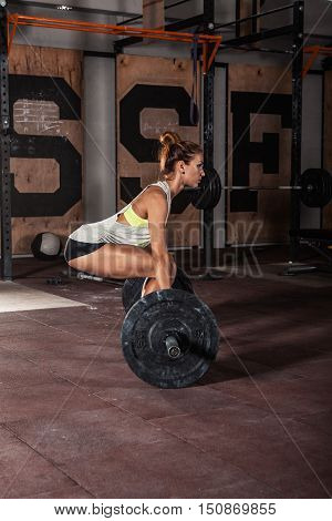 Muscular young fitness woman doing heavy deadlift exercise in gym