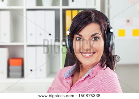Cheerful office employee in pink shirt is listening to energetic music at work during her lunch break. Concept of hedonism