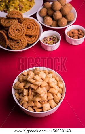 homemade tasty Diwali food or Diwali snacks or Diwali sweets like rava laddu, chakli, sev, shankar pale and chivda or chiwada with dry fruits in white bowls, favourite indian diwali recipe