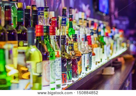 Many bottles of different alcohol by barrels