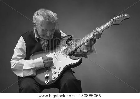 Elderly woman playing a guitar. Selective focus.