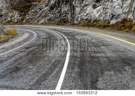 Scenic view of the hairpin bend wet winding road through the pass part of the mountain serpentine in autumn cloudy weather with fog