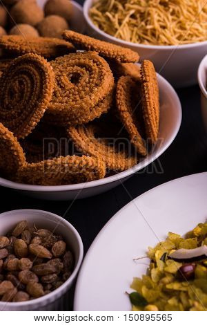 homemade tasty Diwali food or Diwali snacks or Diwali sweets like rava laddu, chakli, sev, shankar pale and chivda or chiwada with dry fruits in white bowls, favourite indian diwali recipe