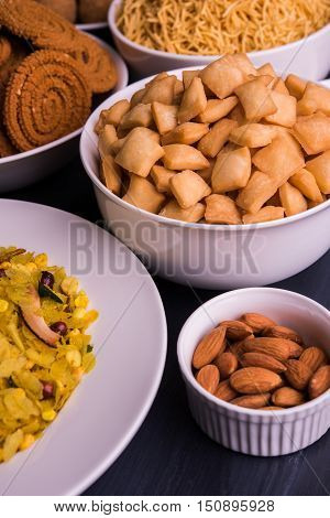 homemade tasty Diwali food or Diwali snacks or Diwali sweets like rava laddu, chakli, sev, shankar pale and chivda or chiwada with dry fruits in white bowls, favourite indian diwali recipe