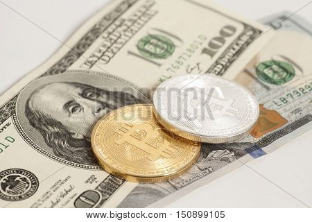 Golden and silver bitcoin coins and one hundred dollar banknotes on white background